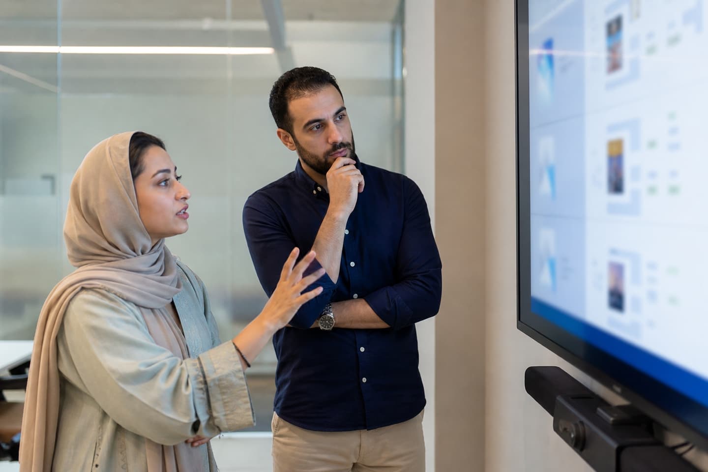 Two hiring leads reviewing candidate evidence together on a meeting-room display